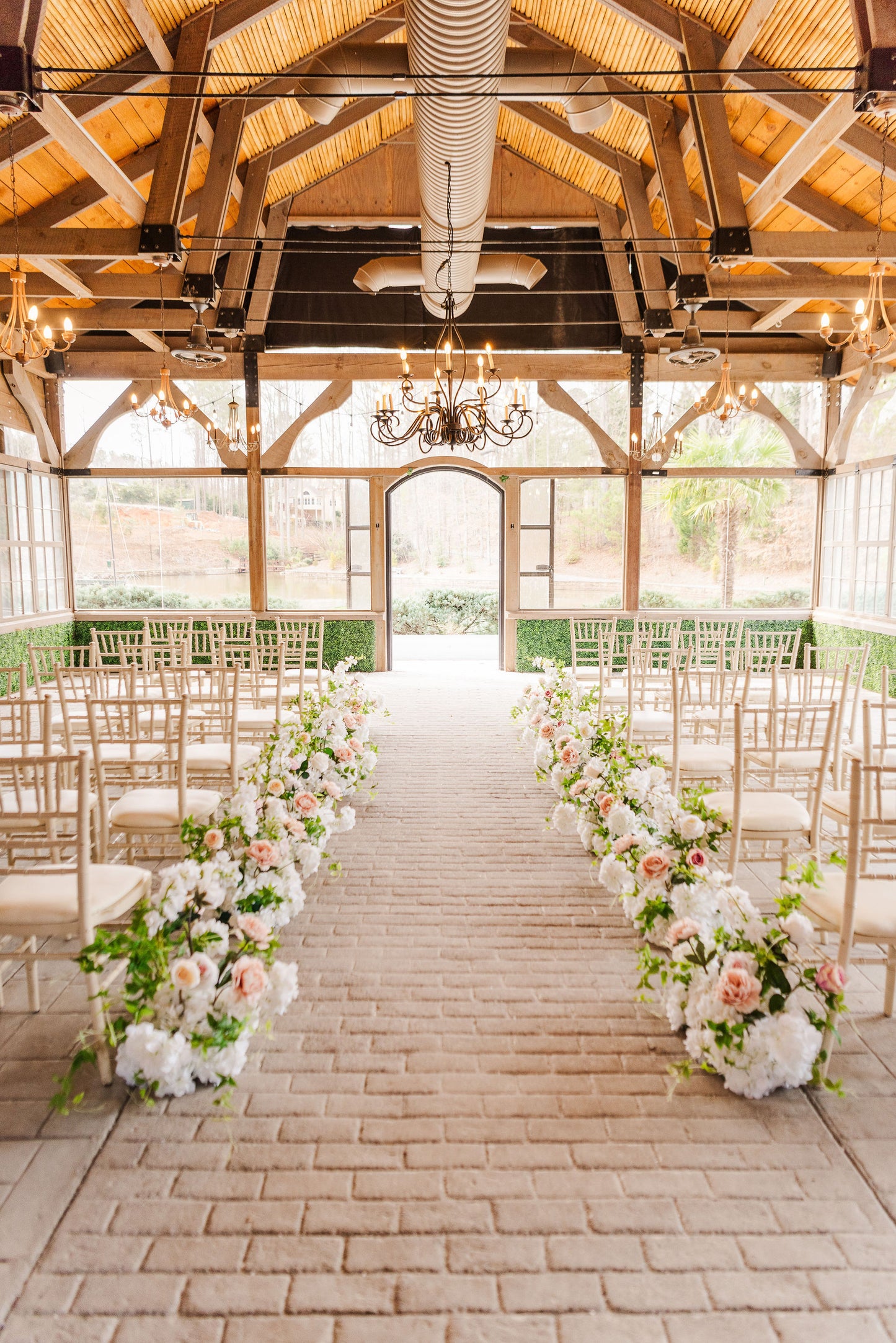 Meadow aisle ground bouquets featuring blush and soft white faux florals with soft greenery, styled directly on the ground to frame a romantic wedding aisle.