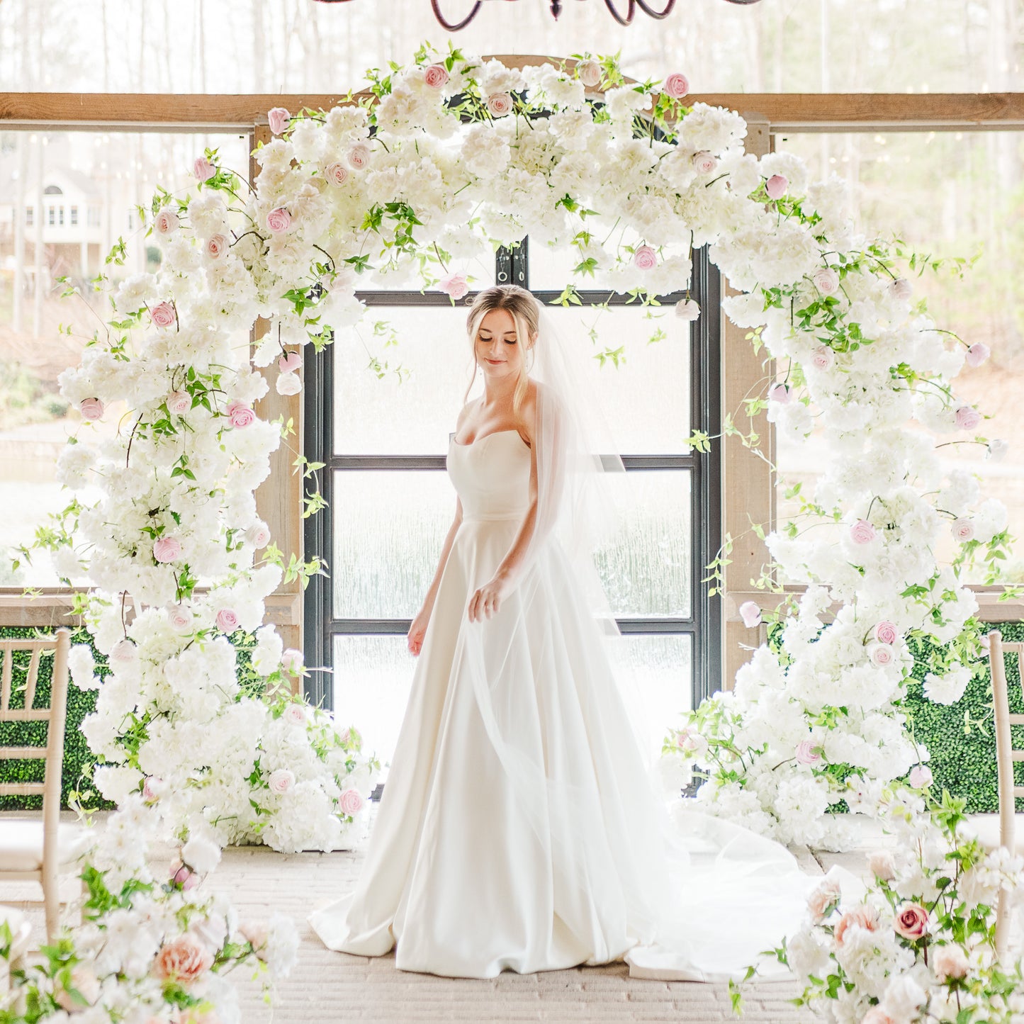 The Meadow Arch styled indoors with soft lighting, bringing a garden-inspired floral presence to an elegant ceremony room.