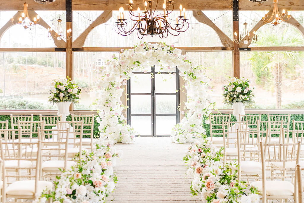 Row of meadow aisle bouquets lining a ceremony path, later repurposed as elegant faux floral centerpieces for reception guest tables.