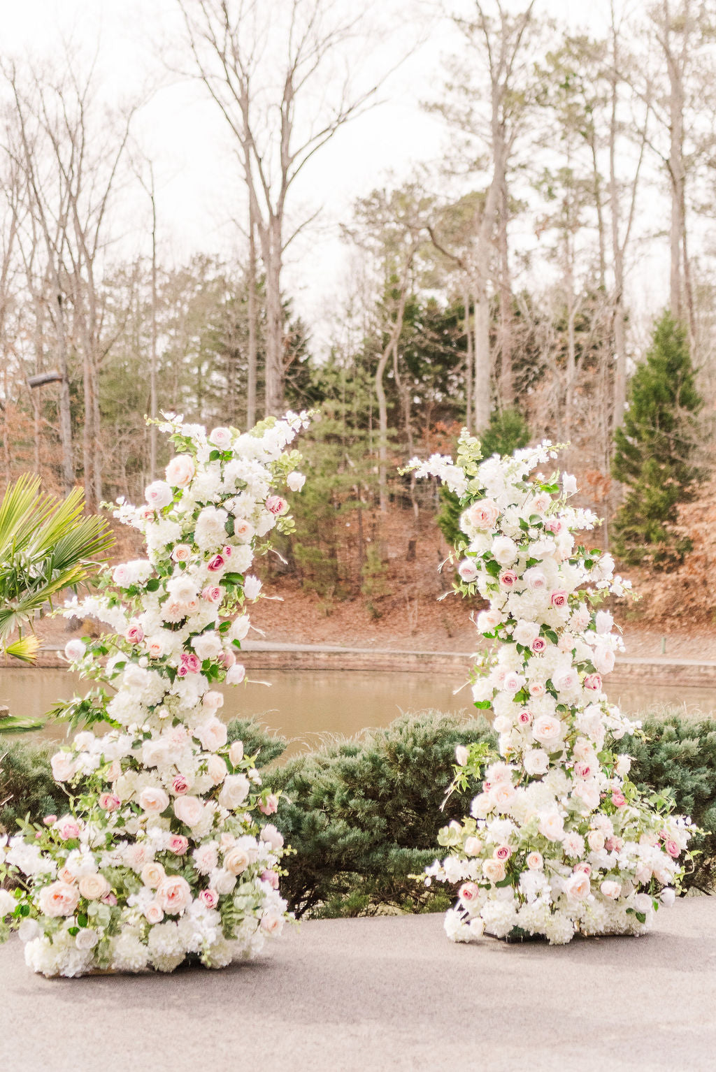 Set of two Everly floral pillars featuring soft white, dusty rose, and blush faux blooms with delicate greenery- perfect for flanking a wedding altar or aisle.