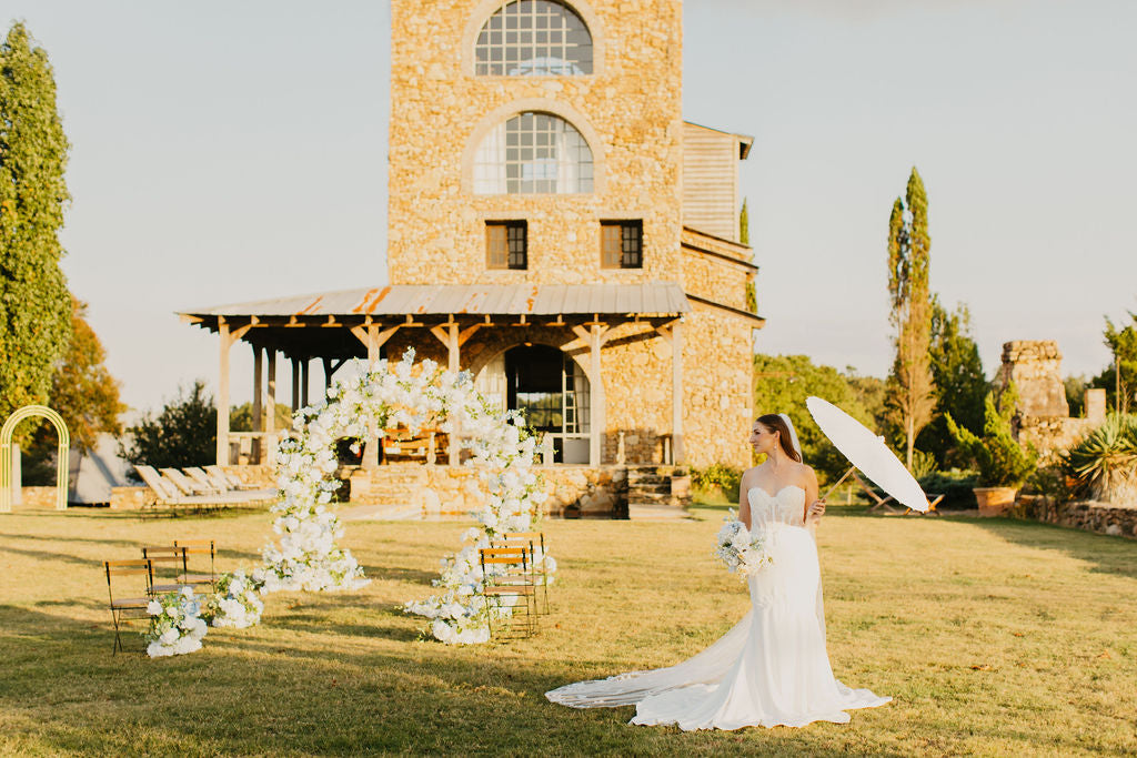 Anastasia aisle bouquet displayed on a white ceremony chair, showcasing fresh spring tones of blue, yellow and white florals.