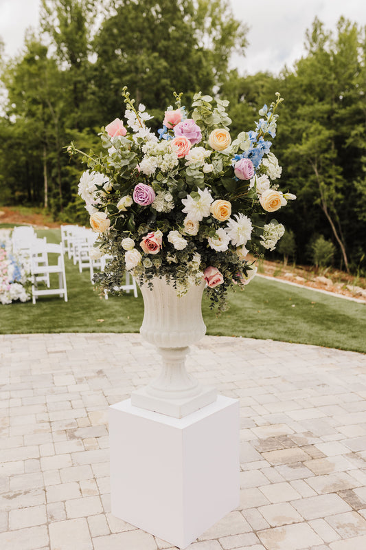 Close up of a wildflower urn filled with lifelike florals including dahlias, roses, delphinium, and greenery in a loose, garden inspired style.