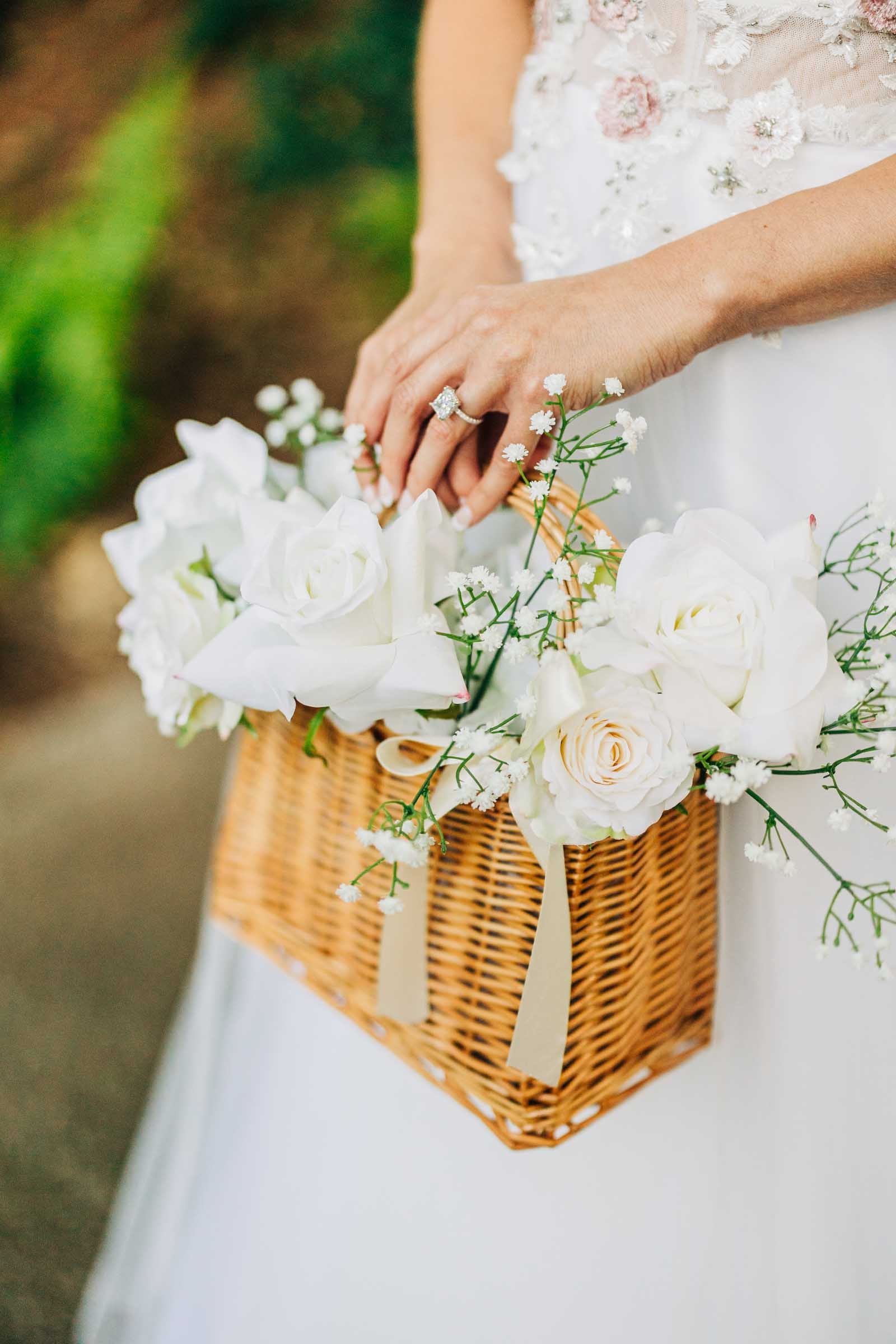 Flower girl holding a hand-tied floral basket, styled with delicate faux blooms and ribbon for a sweet, romantic wedding touch.