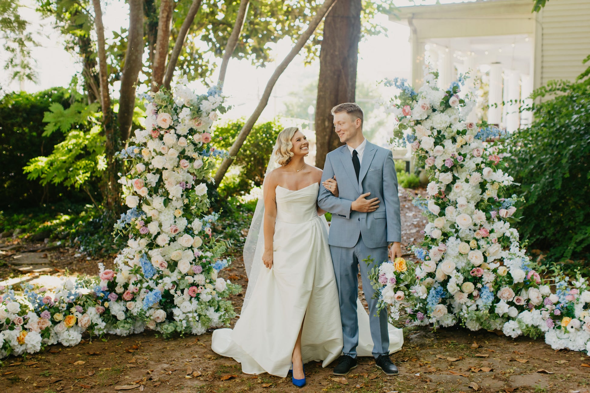 Wide shot of wildflower pillar arches framing a wedding backdrop with guest seating in view, perfect for spring and summer celebrations.